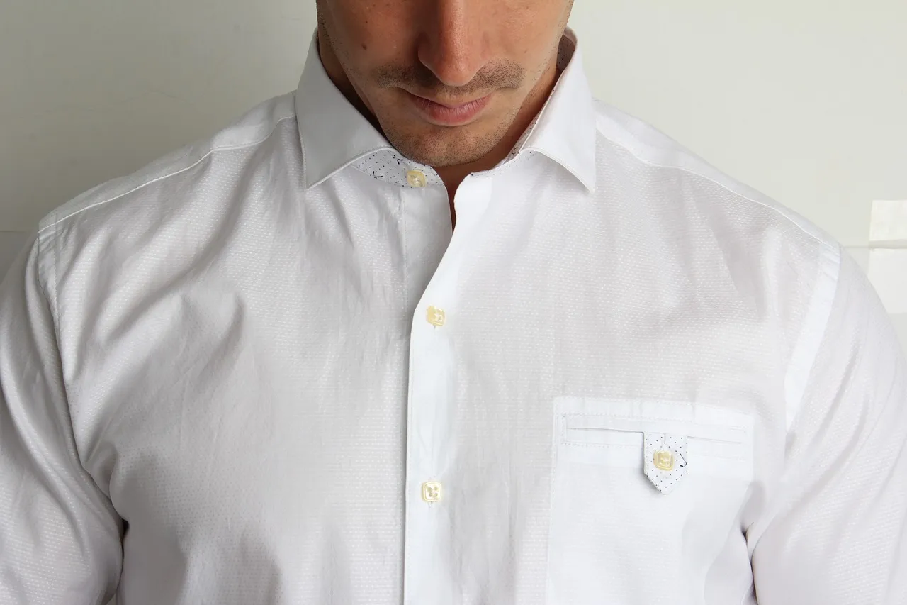 Homme en chemise blanche, cadré du col à la poitrine